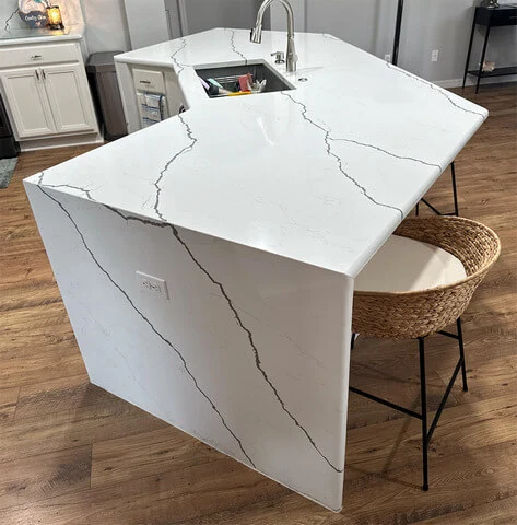 Modern white kitchen island with marble design and stool.