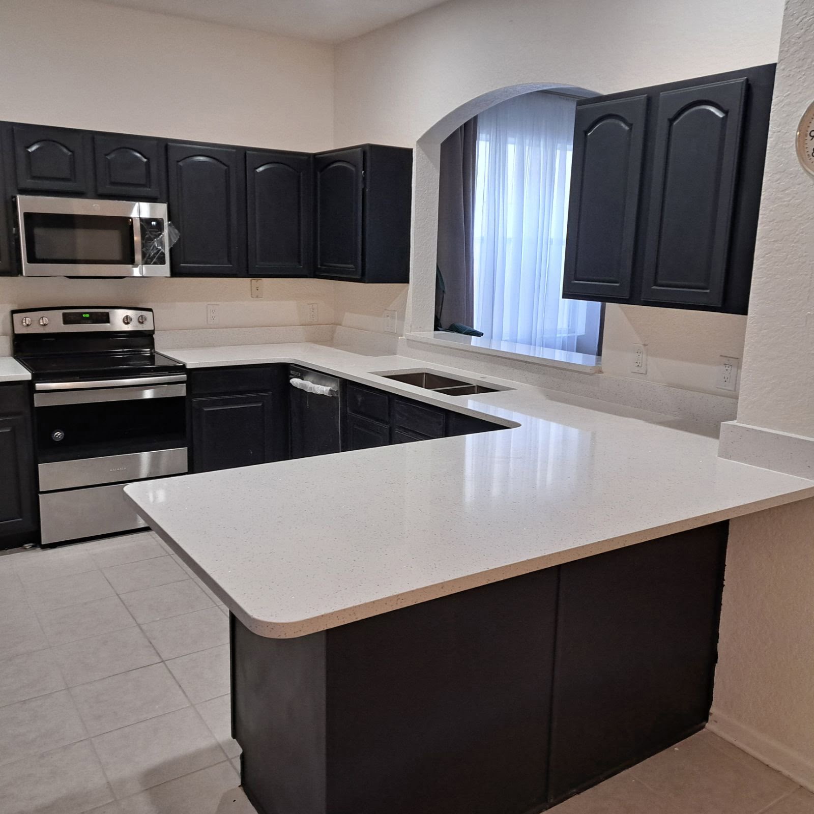 Modern kitchen with black cabinets and white countertops.