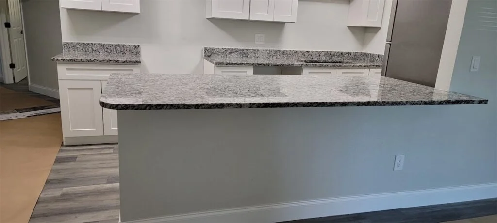 Modern kitchen with granite countertops and white cabinets.