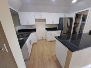 Modern kitchen with white cabinets and stainless fridge.