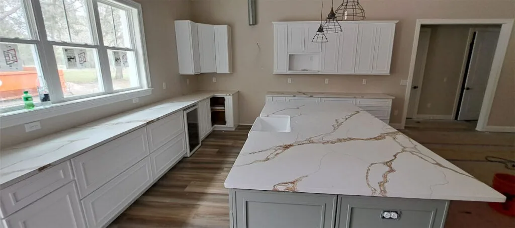 Modern kitchen with marble island and white cabinets.