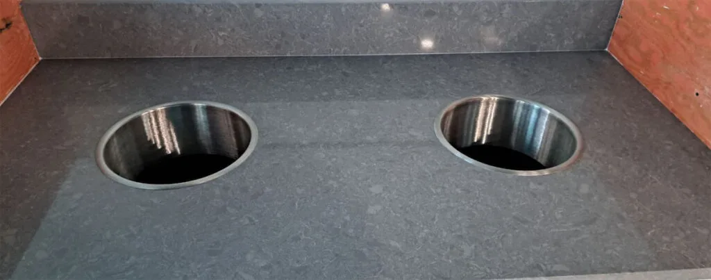 Gray countertop with two circular bin openings.