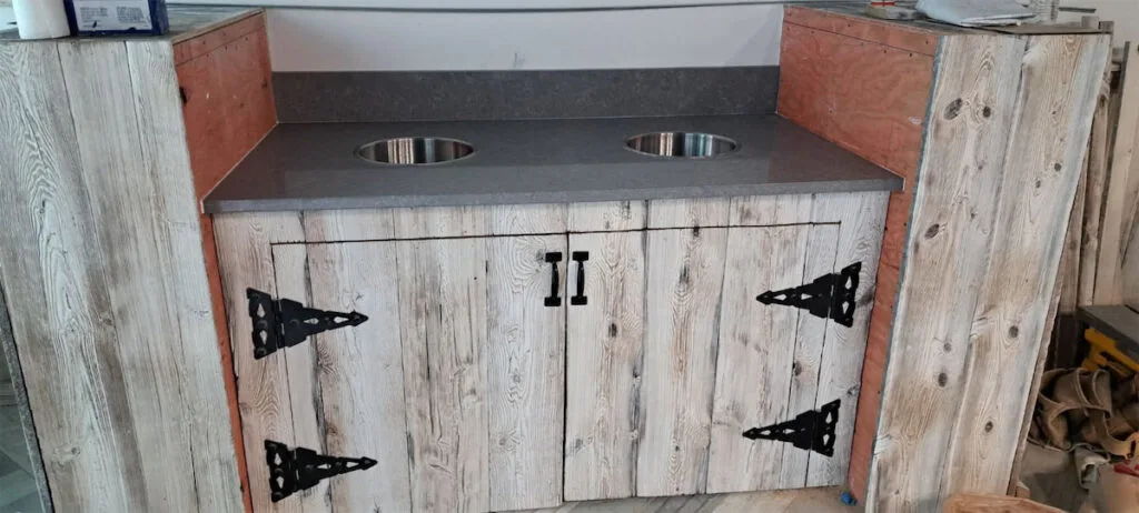 Rustic wooden vanity with dual stainless steel sinks.