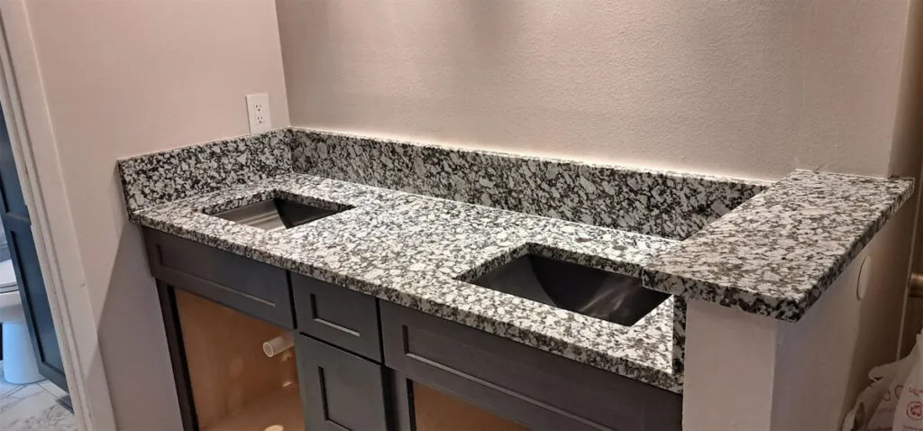 Gray granite countertop with two sink cutouts.