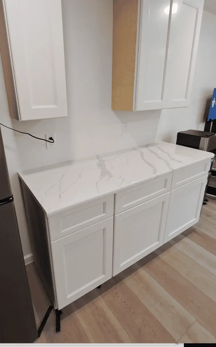 White kitchen cabinets with marble countertop.