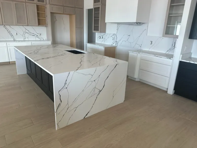 Modern kitchen with marble countertops and wooden cabinets.