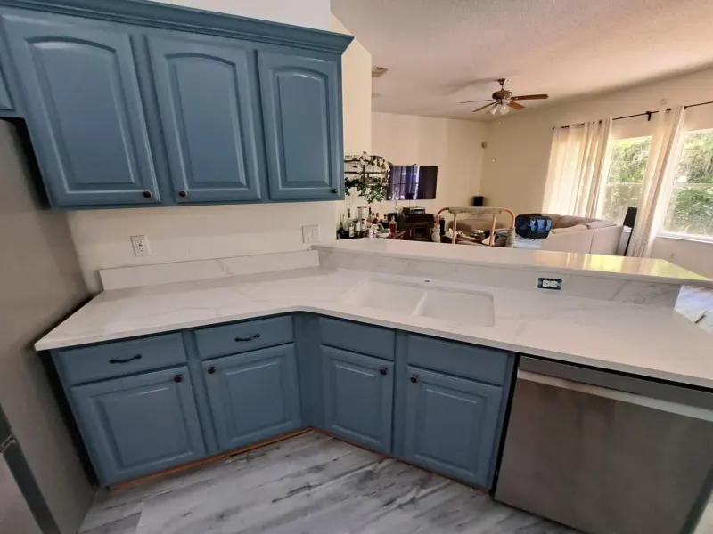 Modern kitchen with blue cabinets and marble countertops.
