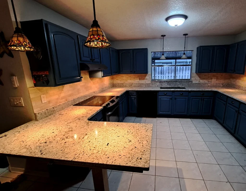 Modern kitchen with granite countertops and dark cabinets.