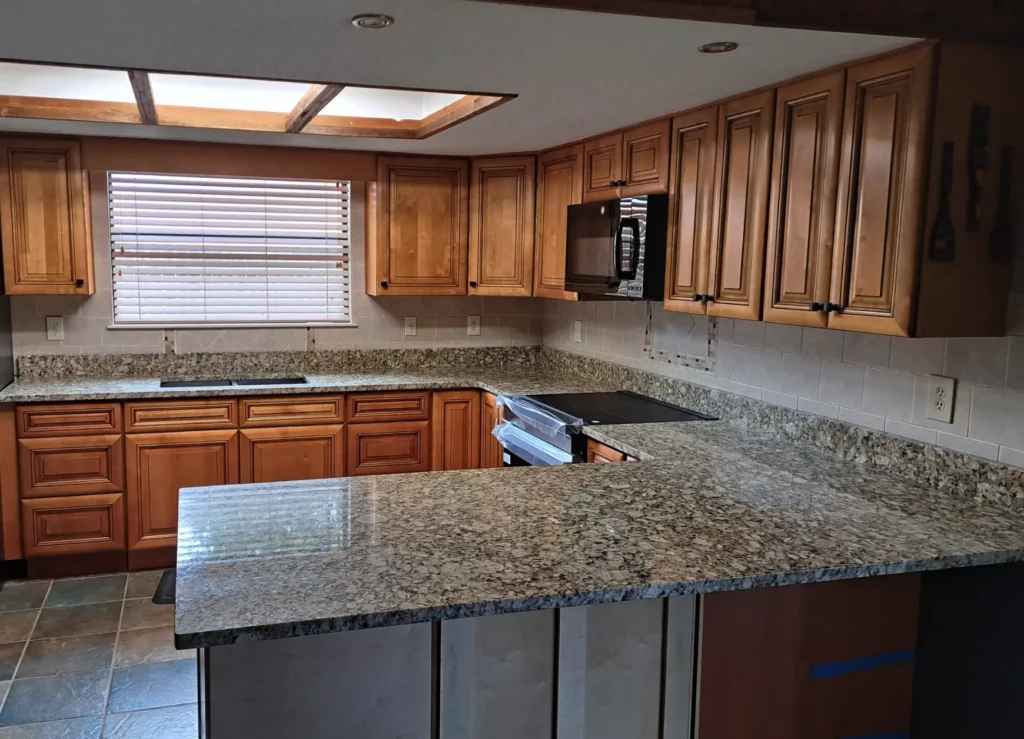 Modern kitchen with granite countertops and wooden cabinets.