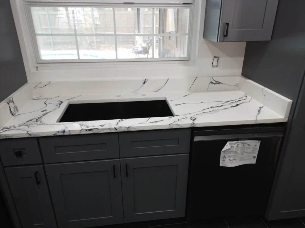 Modern kitchen with marble countertop and gray cabinets.