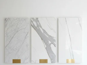 Three polished marble slabs side by side — Carrara, Calacatta, and Statuario — for comparison