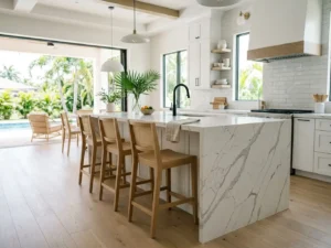 Modern Florida kitchen with a white quartz waterfall countertop island, veining flowing over the edge to the floor, beside sunlit lanai sliders
