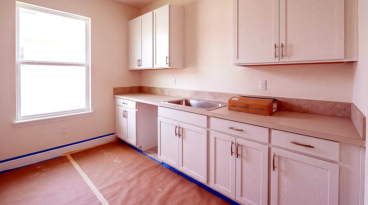 Empty new construction kitchen with white shaker cabinets and plain builder-grade countertop before closing