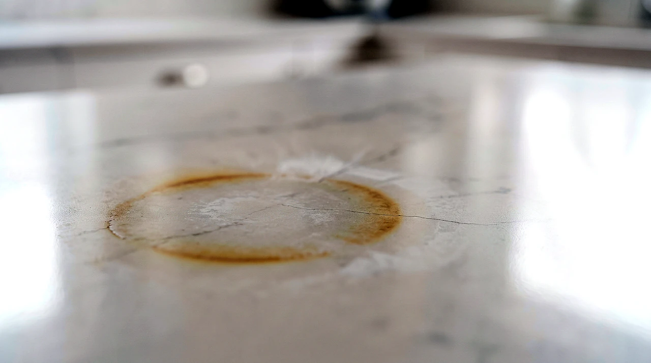 Yellow-brown heat scorch ring burned into a white quartz countertop, the damage excluded by every quartz warranty