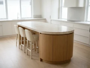 Pill-shaped curved kitchen island with a stone countertop in a bright empty modern kitchen