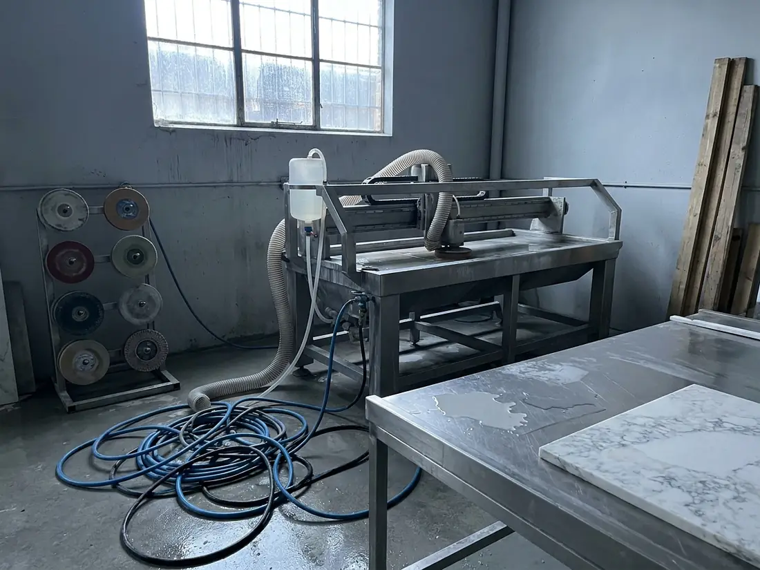 Dust extraction shroud and water feed on stone fabrication equipment in an empty workshop