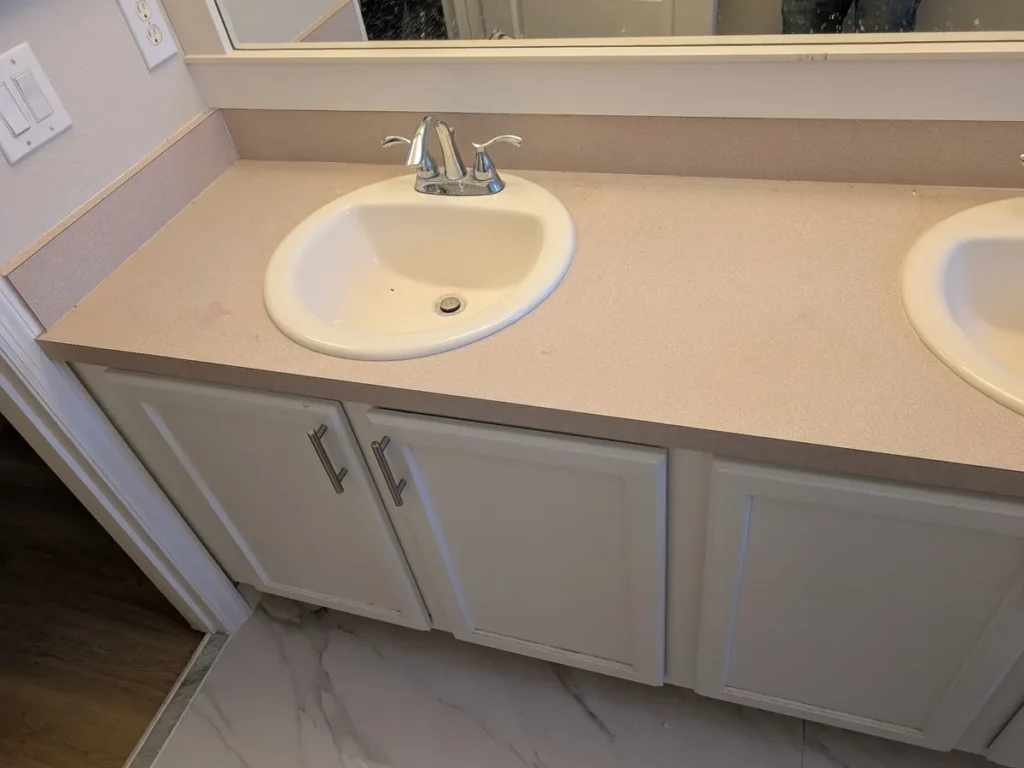 Bathroom before replacement, a dated countertop with drop-in sinks