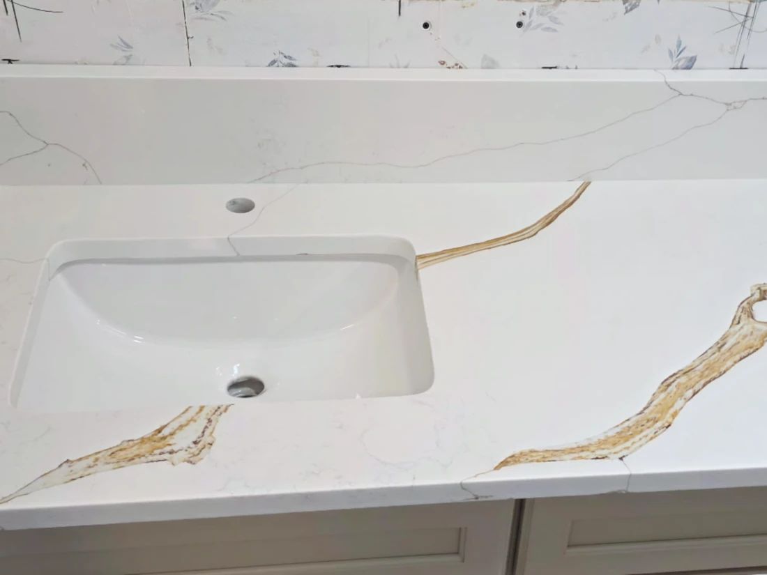 White quartz vanity top with bold gold veins and a rectangular undermount sink