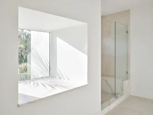 White quartz window sill in a deep stucco window with a quartz-capped shower curb and bench behind