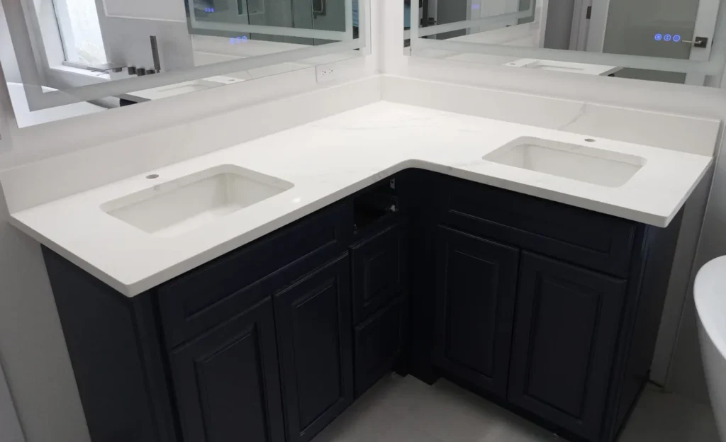 L-shaped Calacatta Tuscany quartz bathroom countertop on navy cabinets